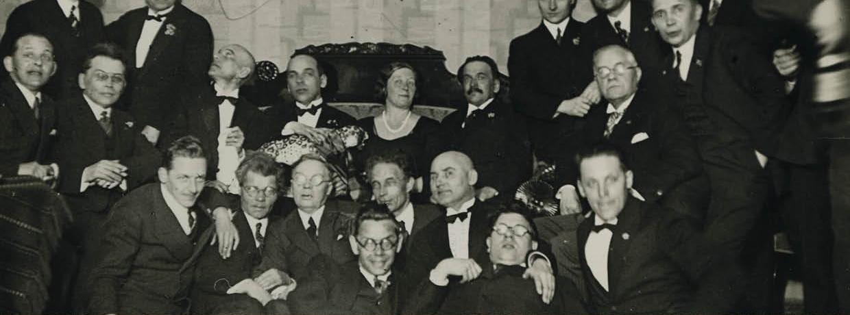 Eesti Kirjanike liidu liikmed 1930. aastatel: keskel istub Marie Under, tema ümber istuvad ja seisavad rõõmsad pidulikes ülikondades meeskirjanikud. 